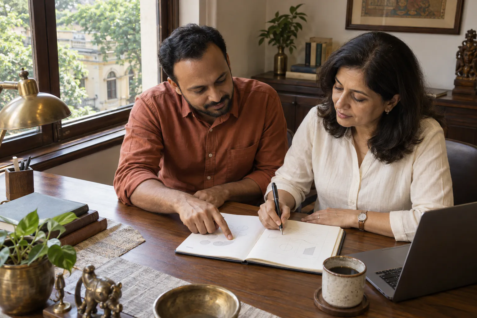 Two Eshcol consultants reviewing an open document together at a desk in a Chennai office